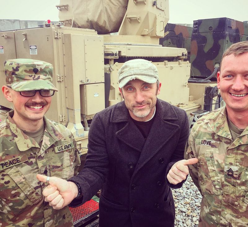 Joel Bryant, standup comedian, posing with Officers Peace and Love at Bagram Air Base in Afghanistan